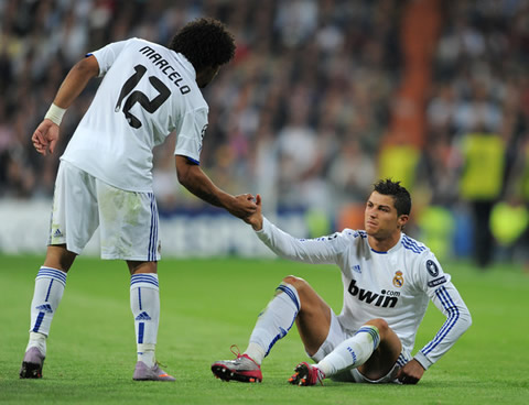 Marcelo reaching out his hand to Cristiano Ronaldo, to help him lifting from the ground in a Real Madrid match in 2010-2011