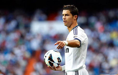 Cristiano Ronaldo holding the ball on his right hand and pointing to something with his left hand, in Real Madrid 2012/2013