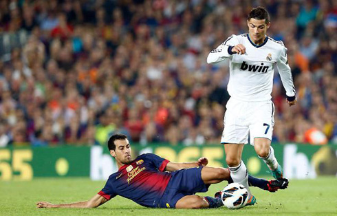 Cristiano Ronaldo trying to avoid a sliding tackle and hard foul from Sergio Busquets, in Barcelona 2-2 Real Madrid for La Liga 2012-2013