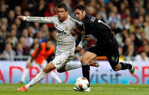 Cristiano Ronaldo running away from a defender, as he escapes him in a Real Madrid game in 2012