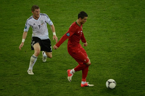 Cristiano Ronaldo holding Bastian Schweinsteiger behind, as he decides what to do with the ball in a game for the EURO 2012