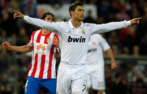 Cristiano Ronaldo stretches his arms to his sides, to celebrate a goal for Real Madrid, with Atletico Madrid's Tiago, behind him