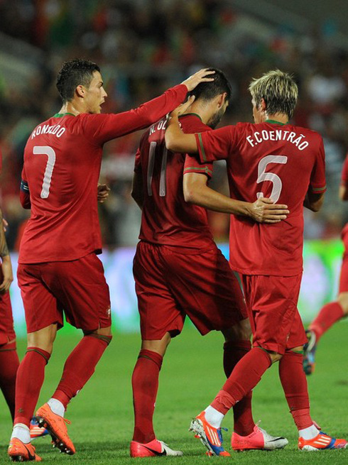 Cristiano Ronaldo touching Nélson Oliveira's head, giving the congratulations to his teammate, as Fábio Coentrão does the same, in a Portugal game in 2012