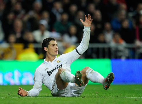 Cristiano Ronaldo on the ground raising his left arm and claiming for a foul