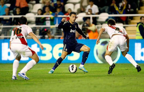 Cristiano Ronaldo trying to get past two Rayo Vallecano defenders, in a match for Real Madrid in 2012-2013