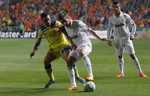 Fábio Coentrão holding and protecting the ball, while Cristiano Ronaldo looks carefully from behind, in Real Madrid 2012