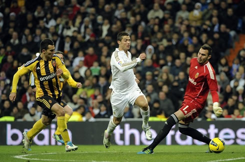 Cristiano Ronaldo about to get past the goalkeeper, while being chased by a defender in a Real Madrid game against Zaragoza, for La Liga 2011-2012