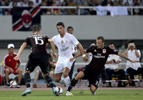 Cristiano Ronaldo dribbling two AC Milan defenders while being pulled by his shirt