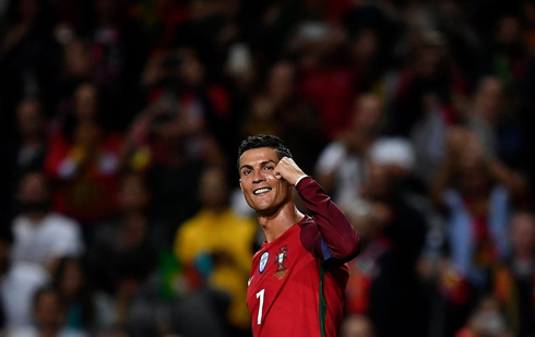Cristiano Ronaldo raises his left arm and smiles to the cameras