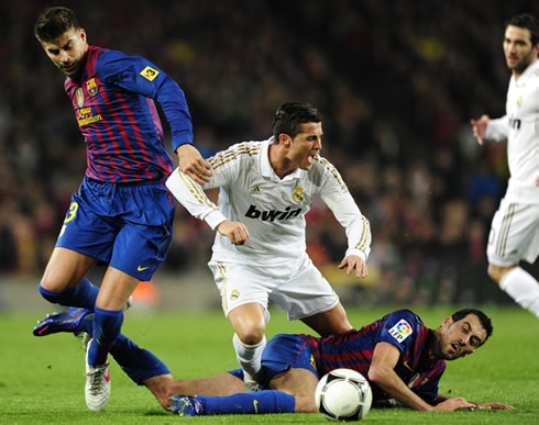 Cristiano Ronaldo being tackled by Sergio Busquets and Gerard Piqué, in Barcelona vs Real Madrid, in 2012