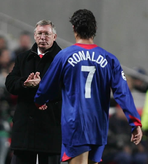 Cristiano Ronaldo in a blue Manchester United jersey, walking towards Sir Alex Ferguson