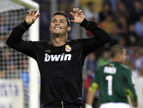 Cristiano Ronaldo in a Real Madrid black jersey, celebrating a goal with his fingers