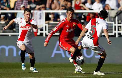 Cristiano Ronaldo dribbling two defenders, in a Real Madrid game for La Liga in 2012