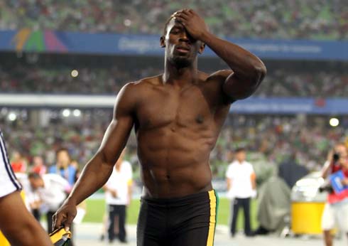 Usain Bolt shows how low his body fat level his, as he gets shirtless after running in the athletics tracks