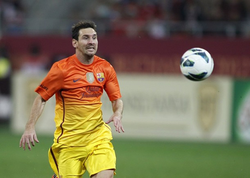 Lionel Messi chasing a ball, with the new Barcelona's orange and yellow shirt, jersey and kit for 2012-2013