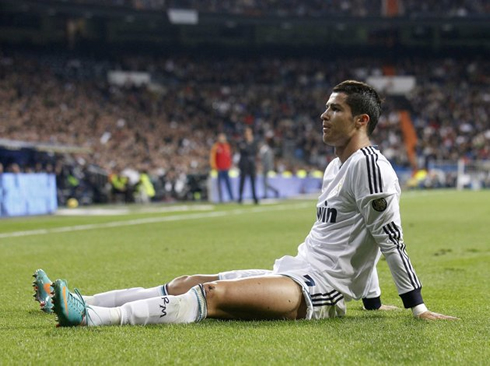 Cristiano Ronaldo with his legs stretched on the pitch, during a game for Real Madrid in 2012-2013