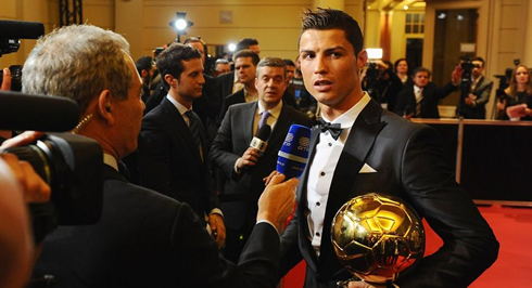 Cristiano Ronaldo talking to journalists while holding the FIFA Ballon d'Or trophy