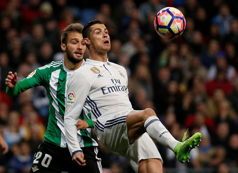 Cristiano Ronaldo holding an opponent on his back as he controls a ball bouncing
