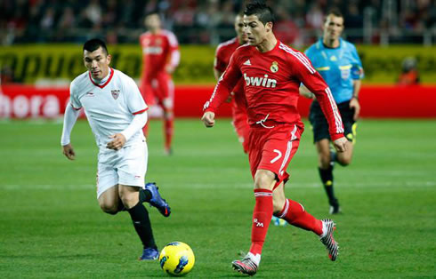 Cristiano Ronaldo running with the ball in Real Madrid red shirt uniform/jersey 2011-2012
