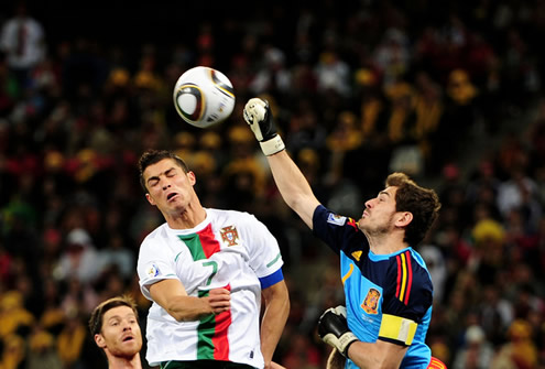 Cristiano Ronaldo jumping and trying to head the ball, while Casillas gets his hand to reach the ball at a higher level