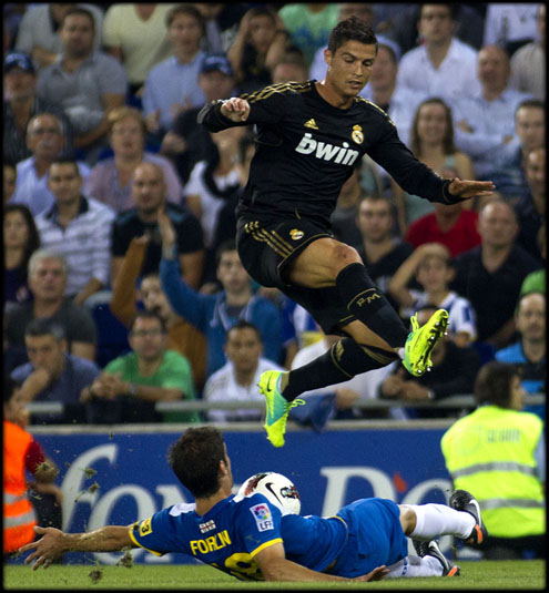 Cristiano Ronaldo jumping over a defender, in Espanyol vs Real Madrid in La Liga 2011-2012