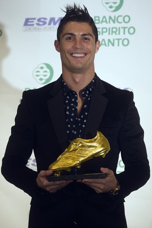 Cristiano Ronaldo in a black suit and black dotted shirt, holding the European Golden Shoe trophy