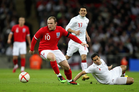 Wayne Rooney playing for England and dribbling a defender