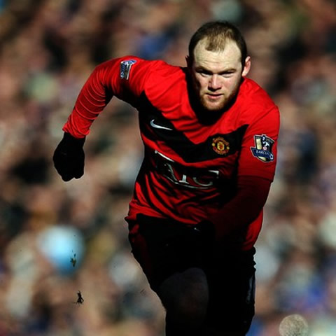 Wayne Rooney appearing from the shadow as he runs to the ball in a Manchester United game