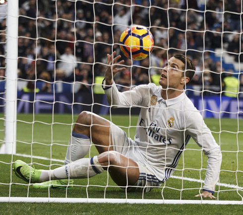 Cristiano Ronaldo slips and falls while grabbing the ball from the back of the net