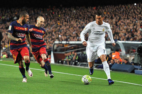 Cristiano Ronaldo moving the ball forward while being followed by Iniesta and Daniel Alves