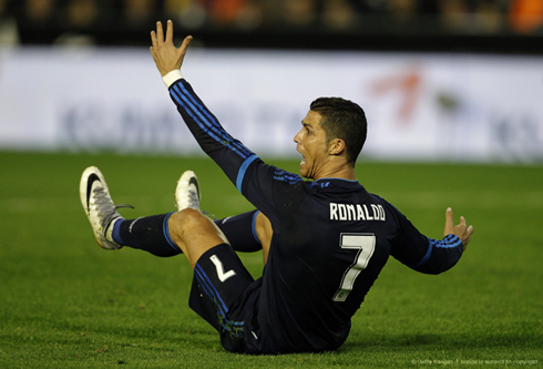 Cristiano Ronaldo sits on the ground and waves at the referee in protest
