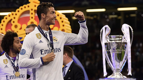 Cristiano Ronaldo picks his Champions League medal as he walks by the Champions League trophy in Cardiff