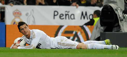 Cristiano Ronaldo lies on the ground and holds to the ball