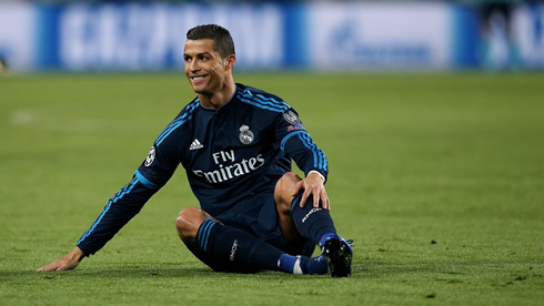 Cristiano Ronaldo sits down on the pitch and smiles