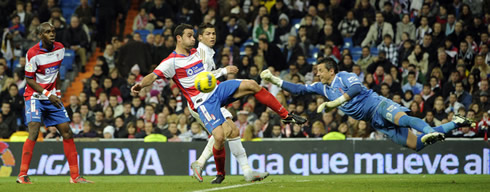 Cristiano Ronaldo trying to reach a cross, but still behind the goalkeeper and a defender