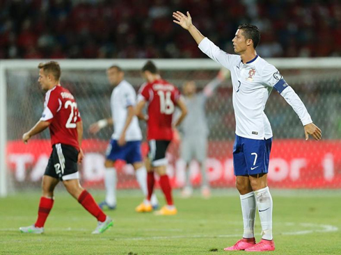 Cristiano Ronaldo raises his arm as calls for someone's attention on the other side of the pitch
