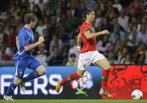 Cristiano Ronaldo running with the ball and being chased by a defender from Iceland