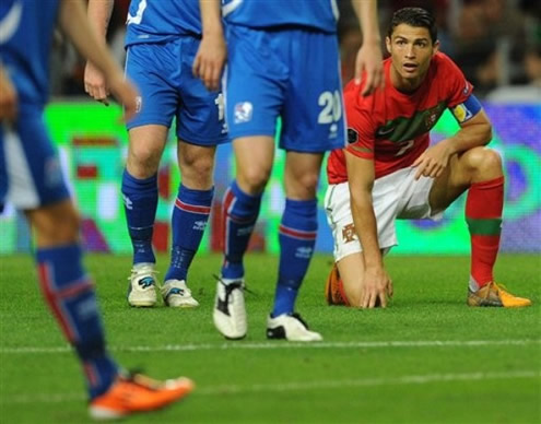 Cristiano Ronaldo with one knee on the ground, looking at someone across the area in Portugal vs Iceland