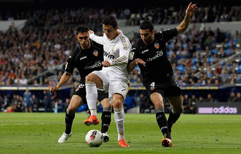 Cristiano Ronaldo stepping on the ball, and protecting it from two defenders at once, in a Real Madrid match for La Liga in 2011-2012