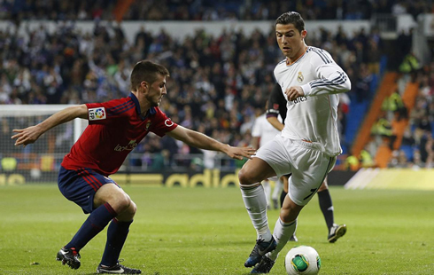 Cristiano Ronaldo taking on an Osasuna defender in a Real Madrid match for the Copa del Rey 2014