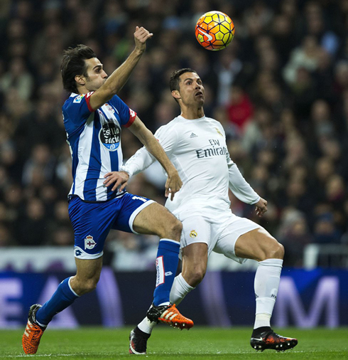Cristiano Ronaldo tries to control a ball coming in the air, as faces opposition from a Deportivo player