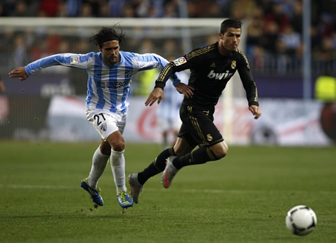 Cristiano Ronaldo being charged by a defender, but holding on as he chase the ball