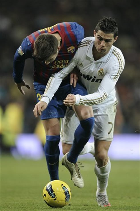 Real Madrid's Cristiano Ronaldo and Barcelona's Gerard Piqué push each other, fighting for the ball in the Clasico