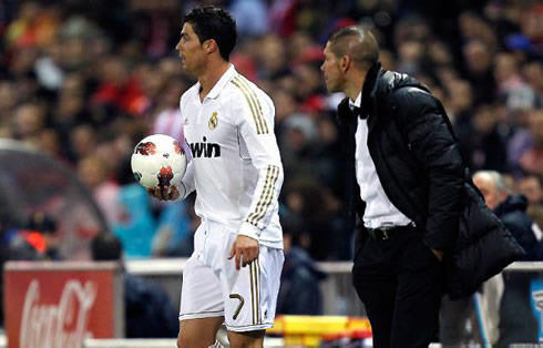 Cristiano Ronaldo holding the ball, while Atletico Madrid's coach, Diego Simeone looks closely