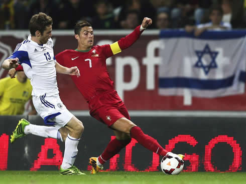 Cristiano Ronaldo stretching to reach the ball, as he gets pressured by an Israeli defender during the FIFA World Cup qualifiers