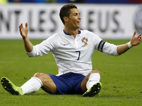 Cristiano Ronaldo sitted on the pitch, smiling and protesting to the referee
