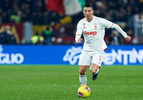 Cristiano Ronaldo sprinting with the ball in a Juventus white jersey