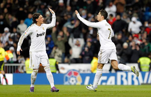 Cristiano Ronaldo greeting Mesut Ozil as he brings the ball under his arm after scoring for Real Madrid, in 2012