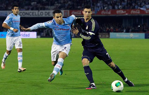 Cristiano Ronaldo pushing away a defender as he guards the ball, in a Real Madrid game in 2012-2013