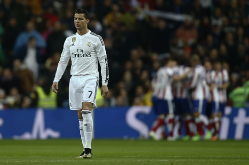 Cristiano Ronaldo walking back to his side of the pitch, as Atletico Madrid players celebrate their team's goal